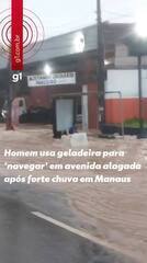 Homem usa geladeira para 'navegar' em avenida alagada após forte chuva em Manaus